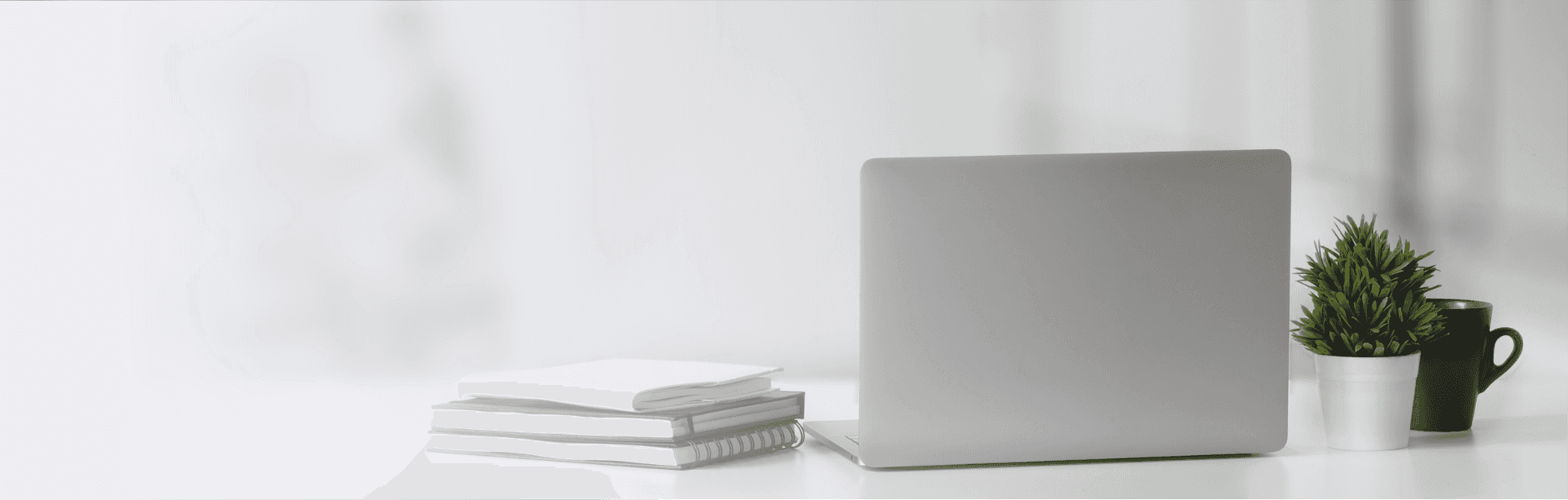 Picture of an unbranded laptop sitting on a clean desk with notebooks beside it